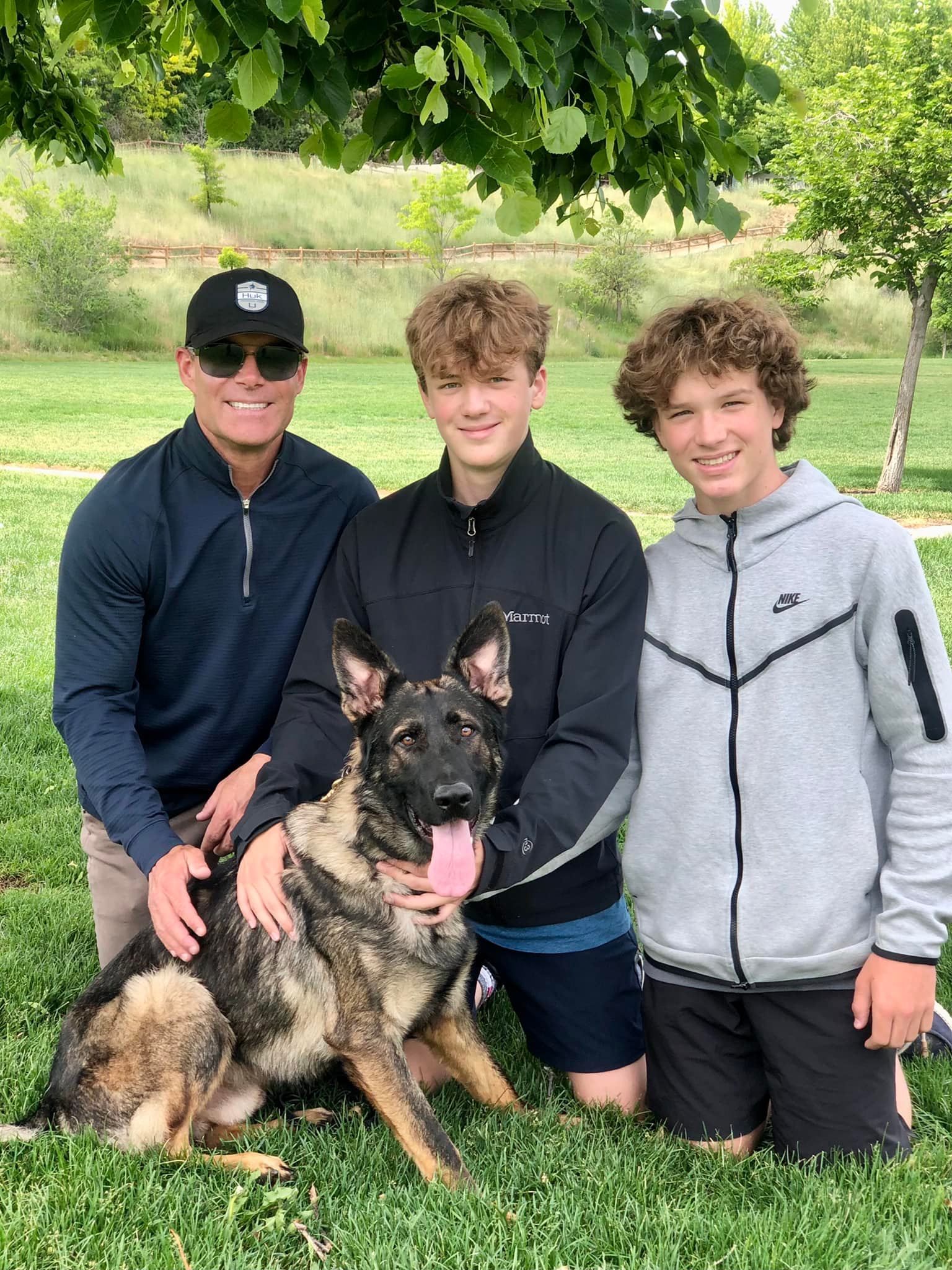 Family with German Shepherd dog in park.